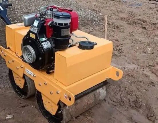 Walk-behind double drum roller on a soil site