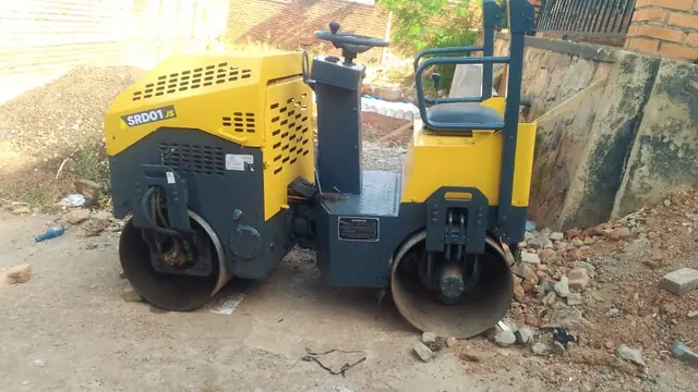 Ride-on roller compactor with two steel drums, parked on a building site