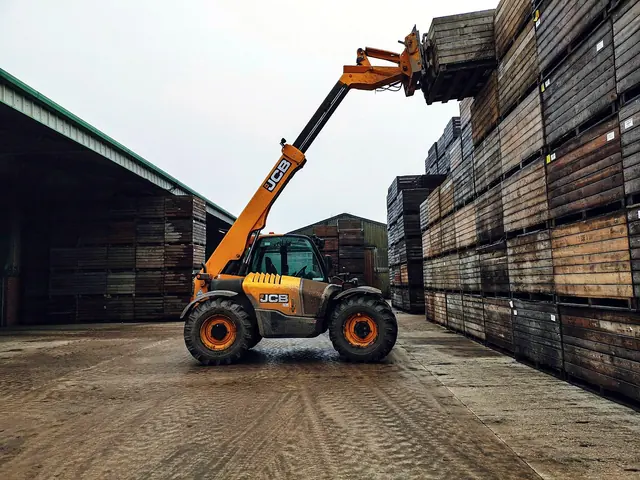 Telehandler lifting a stack of crates in a yard